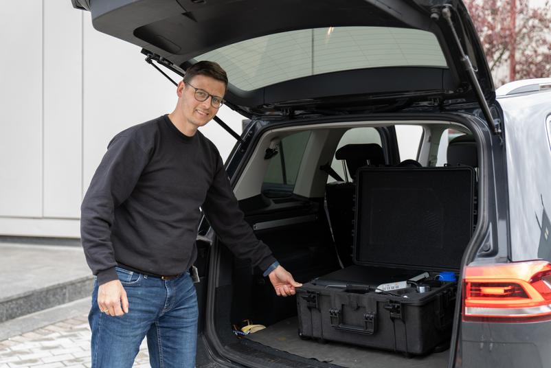 A technikus kiveszi a bőröndöt a kalibráló berendezéssel az autóból